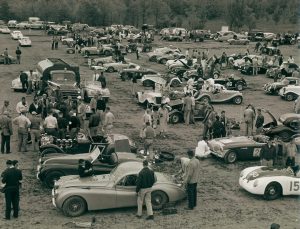  The Paddock at Watkins Glen in 1954 is filled with a representative sampling of the caars being raced, including Jaguar XK120 coupes and roadsters, a couple of Porsche 356 roadsters and a coupe, an Austin-Healey 100 and lots of T-series MGs, all getting their numbers on and preparing to go racing. Photo: Alix Lafontant