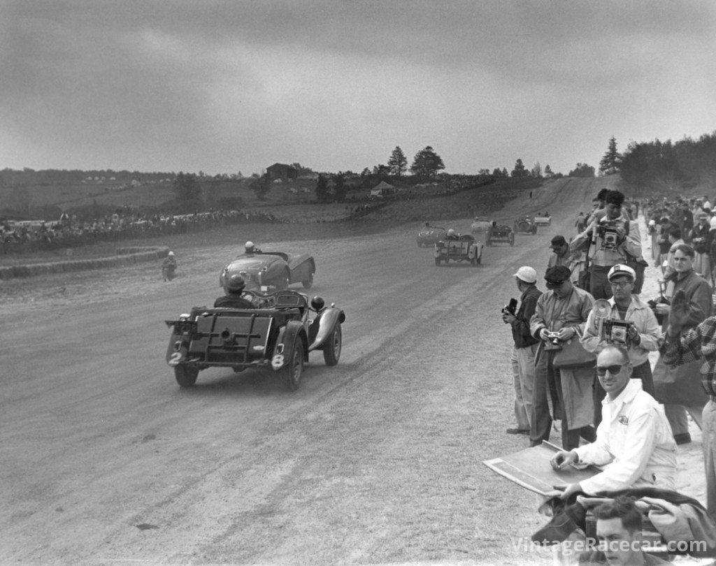  The Austin-Healey 100 pace car leads the pack for a single pace lap prior to the green flag to start the Seneca Cup contest. Following it up the hill are the 8C Alfa, Constantine Jag, Wyllie Jag, the #22 Jag of Cam Argetsinger, and three modified MGs including the #28 TD of Charles Limbacher. Photo: Alix Lafontant
