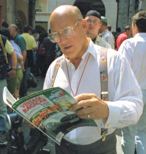 Stirling Moss enjoys a good read during scrutineering. 