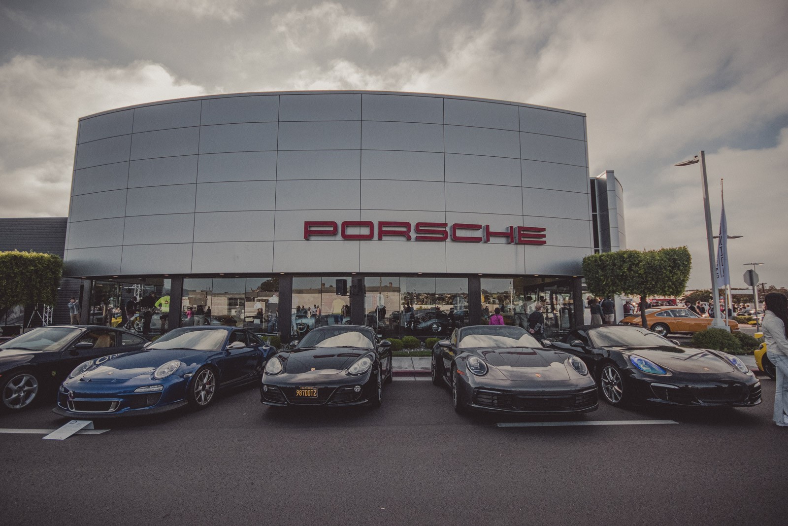 A variety of new Porsches lined up on Del Monte Blvd. in front of the Porsche dealership showroom