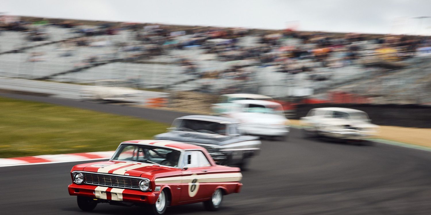 The Ford Falcon of Trevor Buckley leads a gaggle of cars around the tricky, off camber Paddock Hill Bend.