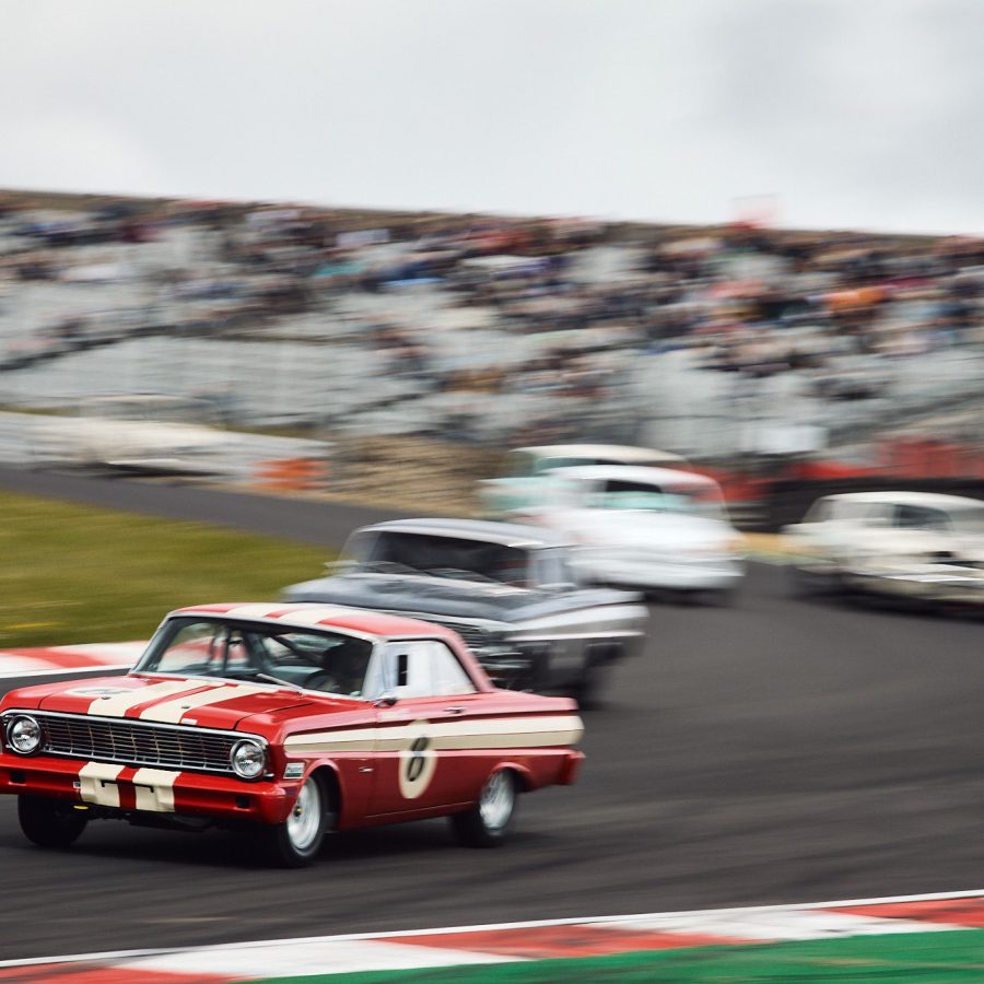 The Ford Falcon of Trevor Buckley leads a gaggle of cars around the tricky, off camber Paddock Hill Bend.