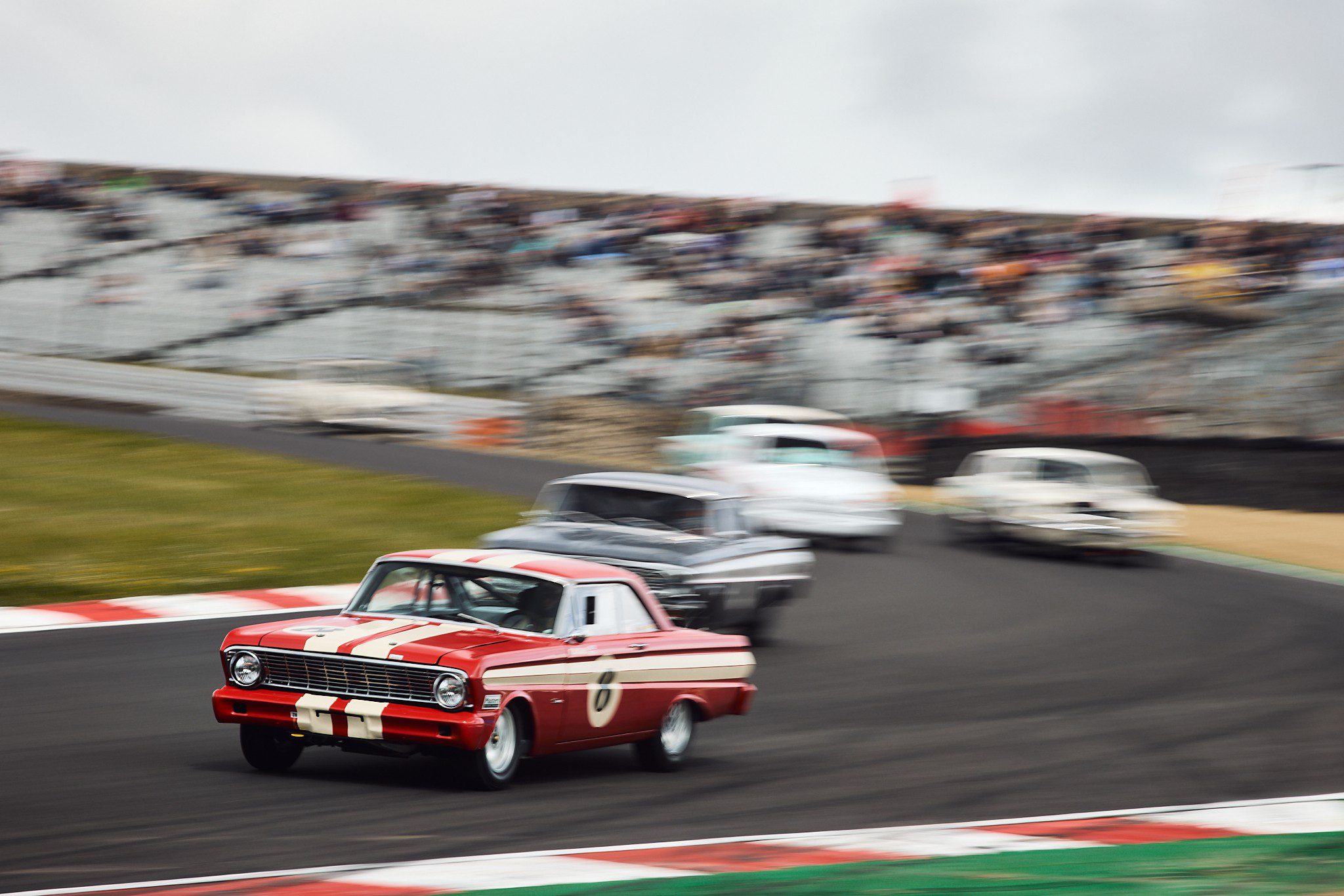 The Ford Falcon of Trevor Buckley leads a gaggle of cars around the tricky, off camber Paddock Hill Bend.