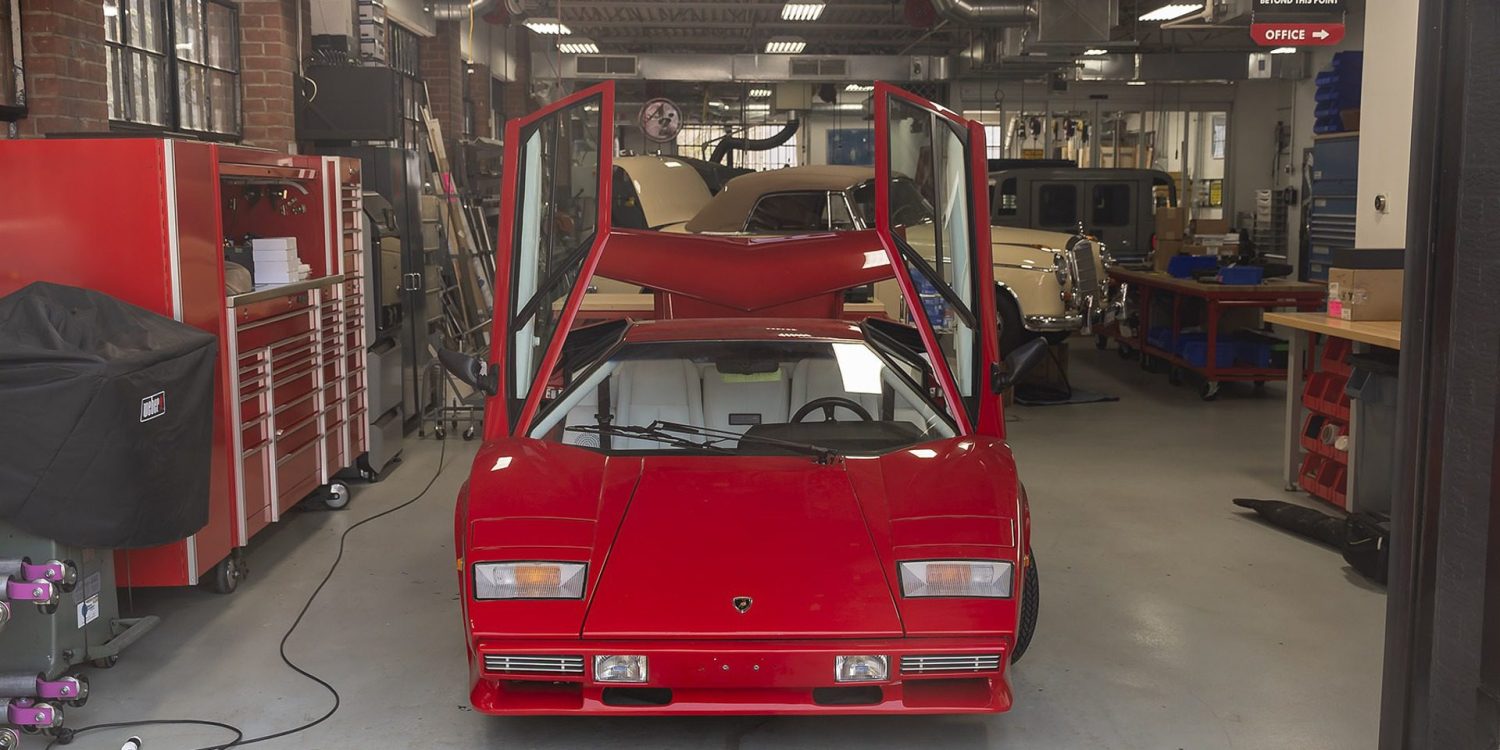 Red sports car with vertical doors raised in Ai Design shop