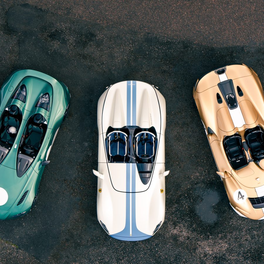Aerial image showing a green Aston Martin V12 Speedster, white and blue Ferrari Monza SP2 and gold and white McLaren Elva.