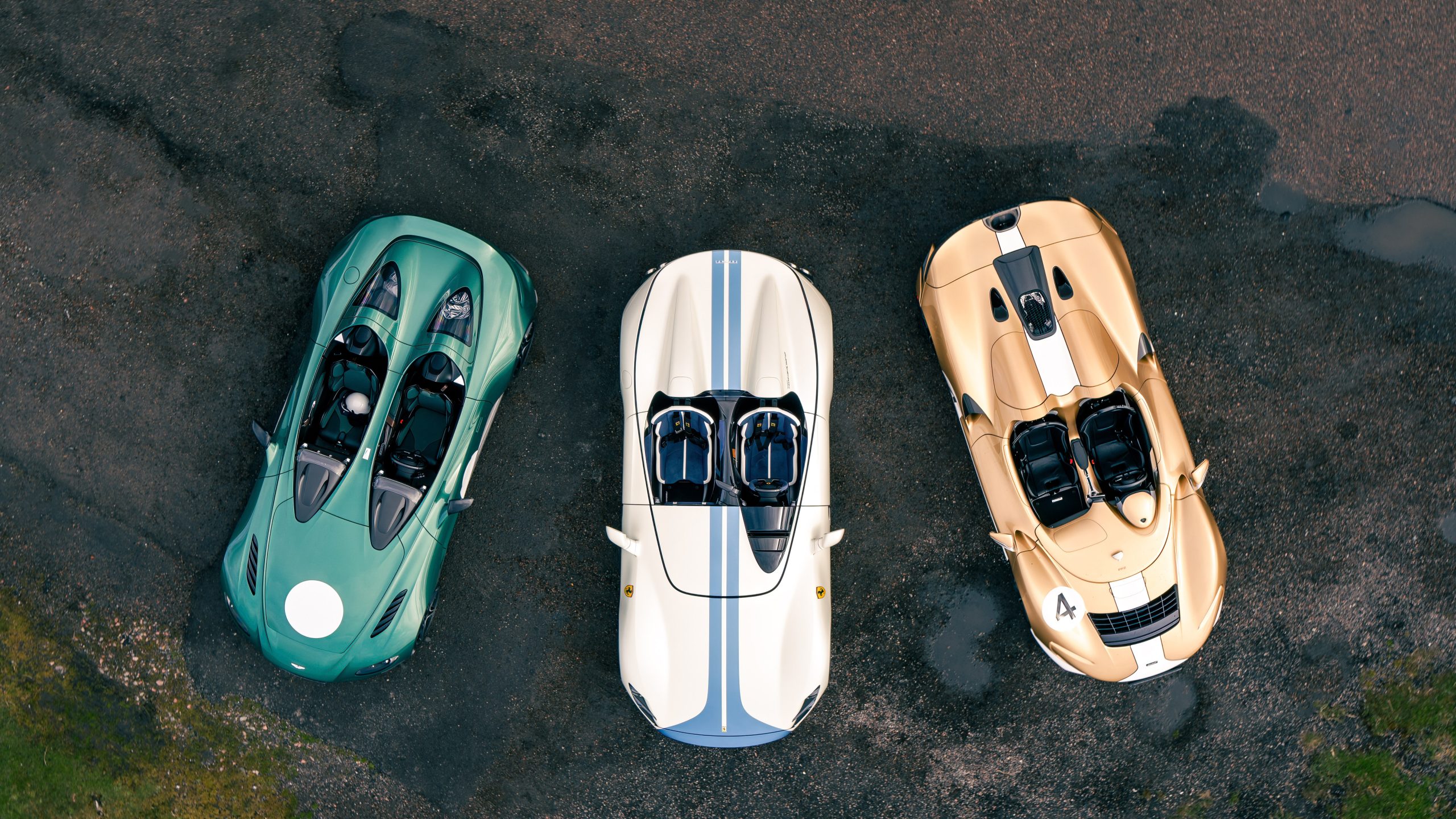 Aerial image showing a green Aston Martin V12 Speedster, white and blue Ferrari Monza SP2 and gold and white McLaren Elva.