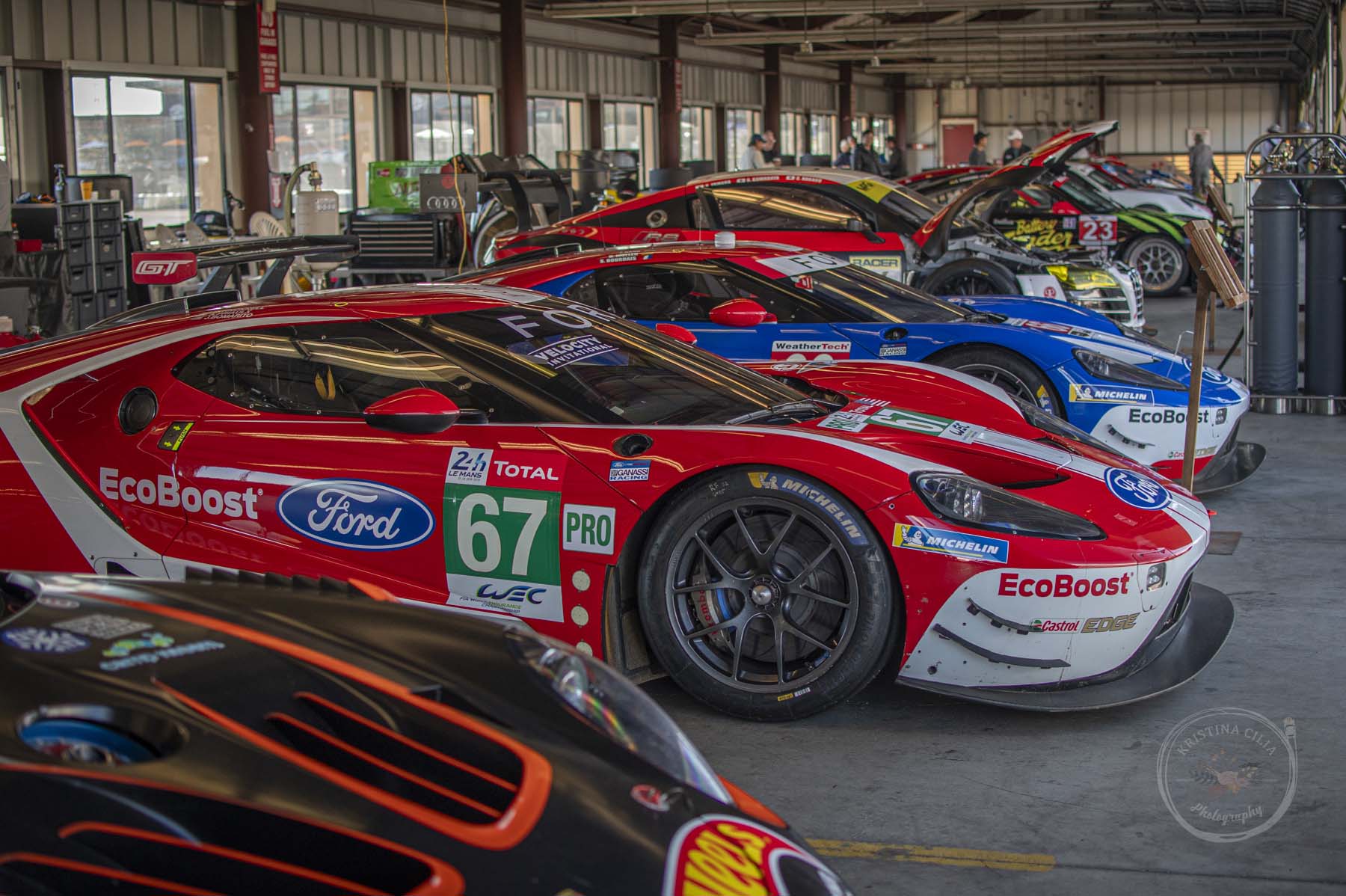 Group 9 racercars are lined up in a garage at Sonoma Raceway during Velocity Invitational