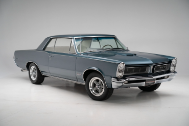 Three-quarter side view of a restored 1965 turquoise Pontiac GTO coupe