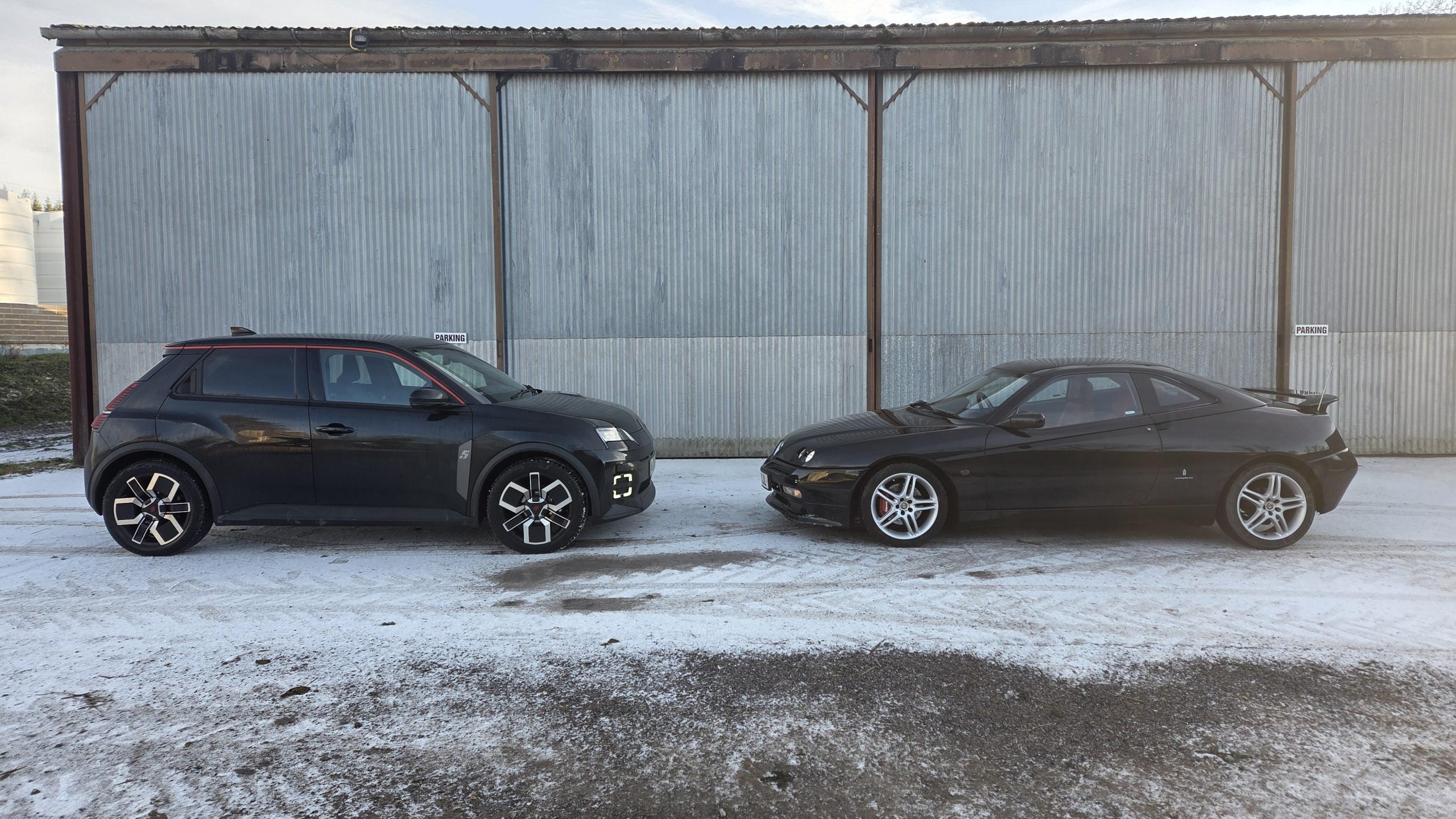 Black Renault Megane E-Tech Electric facing a black Peugeot 406 Coupe