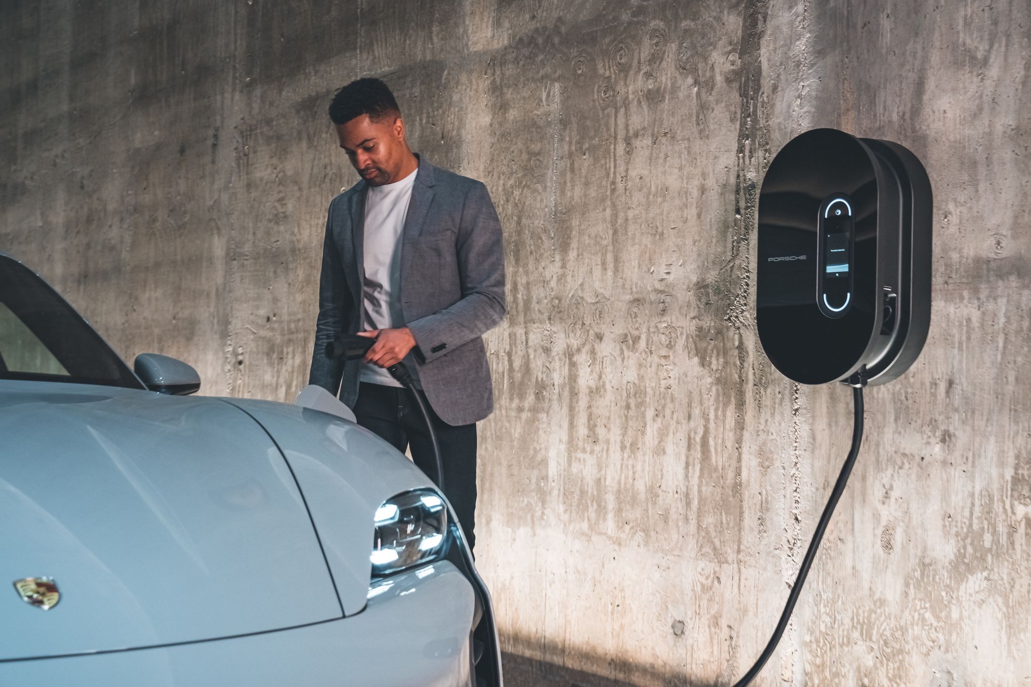 Man charging a blue Porsche Taycan at home